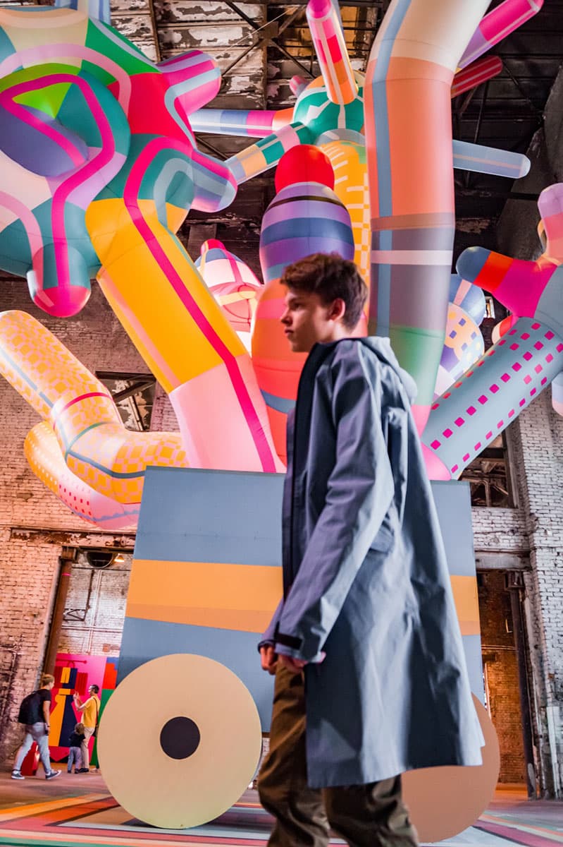 male walking in front of a colorful art display